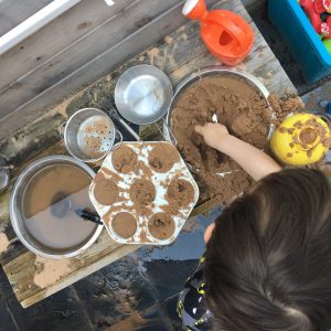 child playing with sand in a mud kitchen
