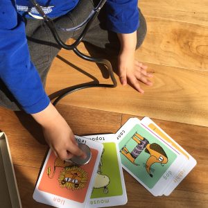 Young boy with a stethoscope pretending to listen to a lion on a flashcard