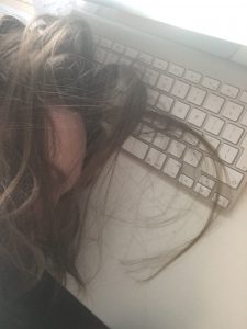 Exhausted mother with her head resting on a computer keyboard