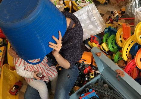 Exhausted mother with a young child sitting amongst a mess of toys