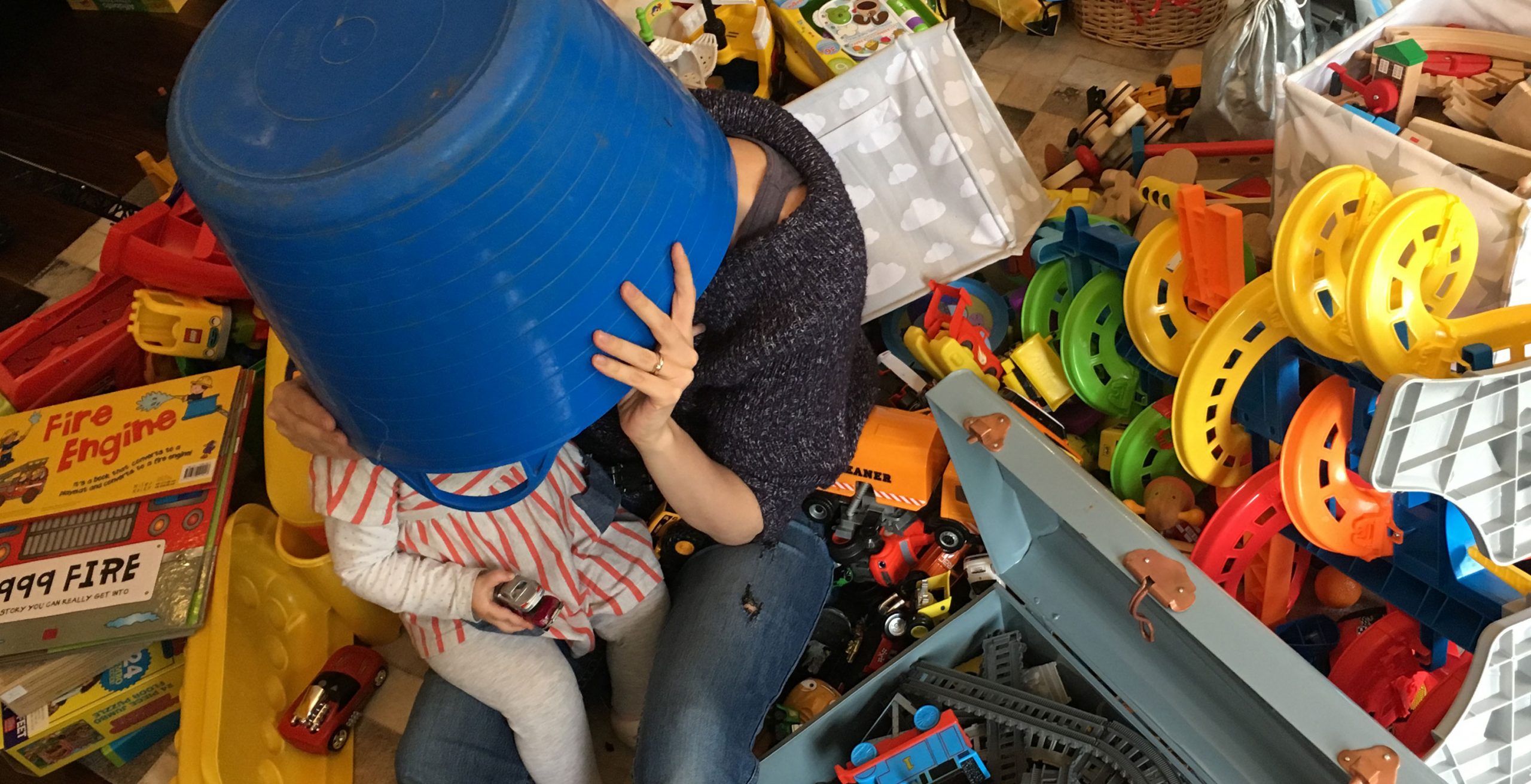 Exhausted mother with a young child sitting amongst a mess of toys