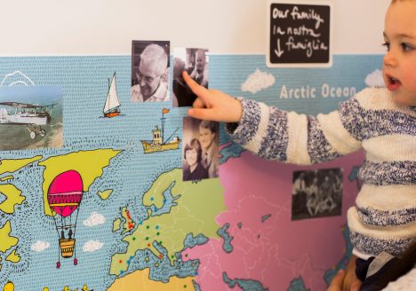 child looking at a map of the world with family photos around it